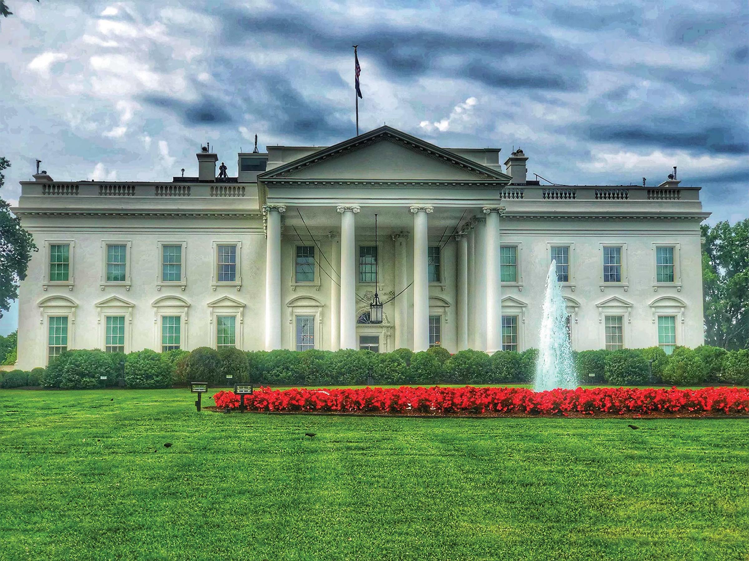 The White House in spring under cloudy skies with red flowers and a fountain